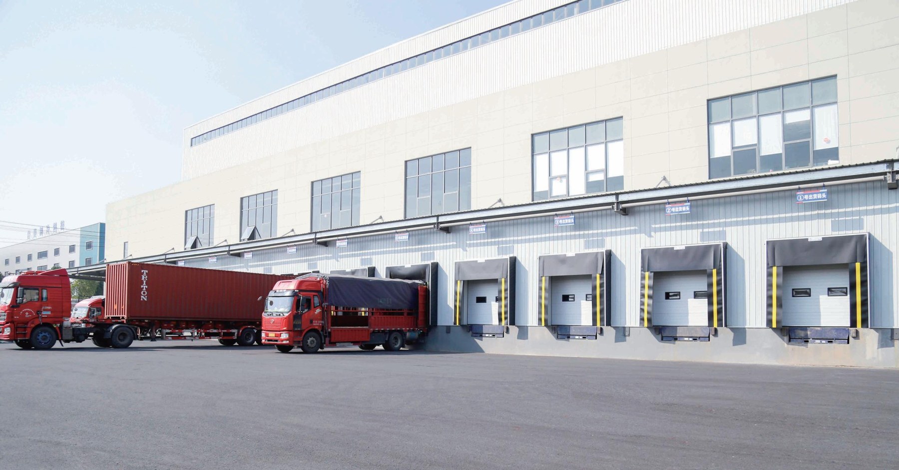 Hydraulic dock leveler installed at a logistics loading dock with sectional doors and dock shelters
