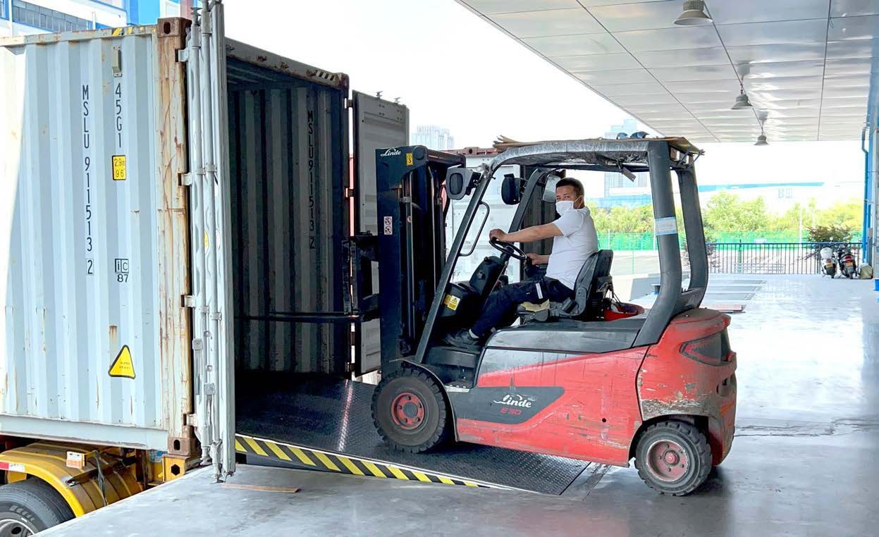 Forklift crossing a hydraulic dock leveler into a container