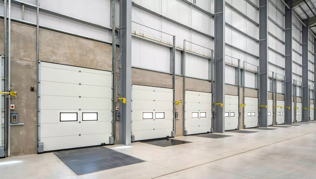Multiple industrial sectional overhead doors installed inside a large industrial warehouse