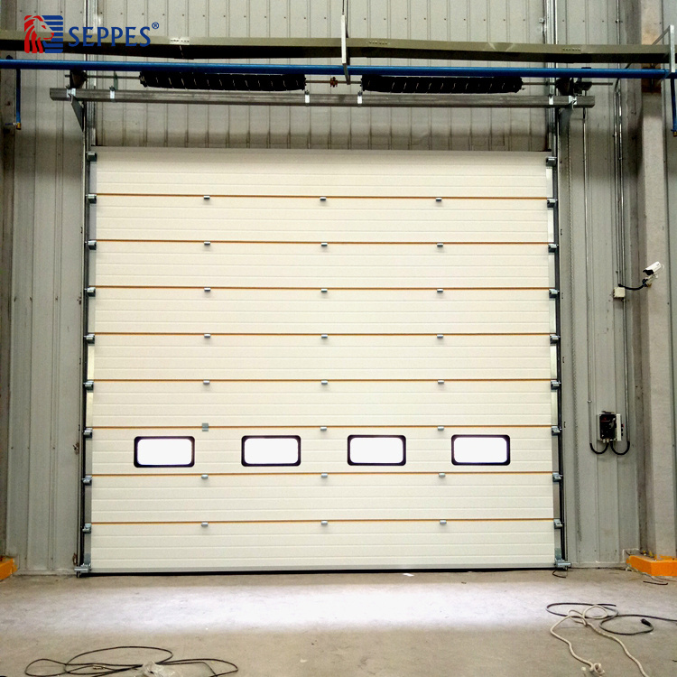 SEPPES insulated industrial sectional overhead door with vision windows at factory entrance